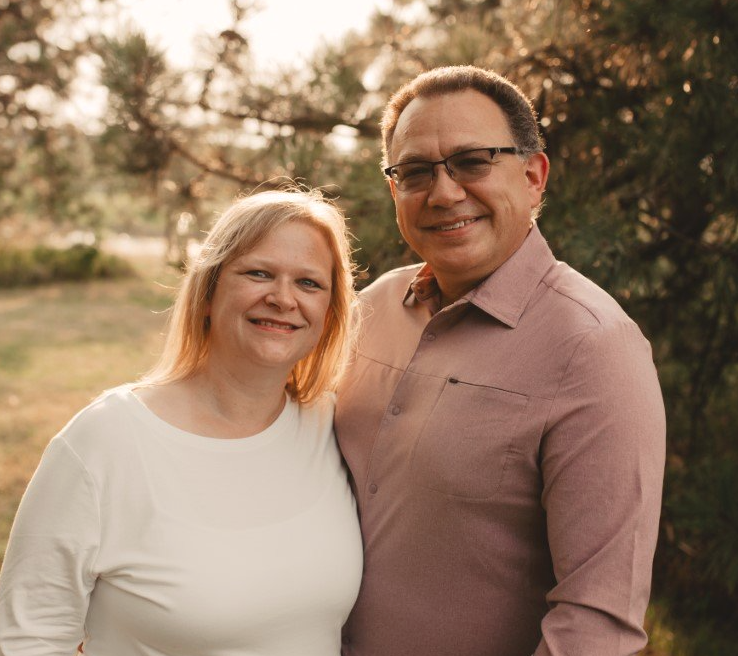 A man and a woman are posing for a picture and smiling for the camera.