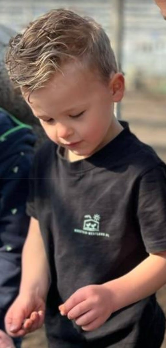 Jong kind in zwart T-shirt kijkt naar beneden.
