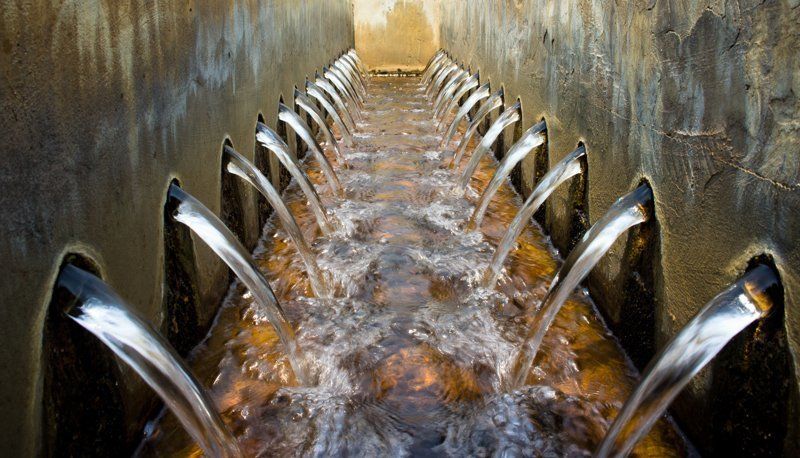 L'acqua scorre da più getti in un lungo canale.