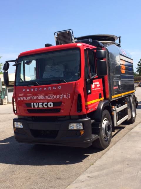 Camion aspiratutto Iveco Eurocargo rosso, parcheggiato all'aperto alla luce del giorno.