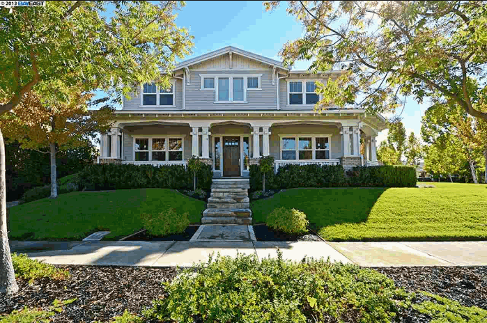 Two-story light gray house with porch, green lawn, and trees on a sunny day in Livermore, CA Sellers Agent