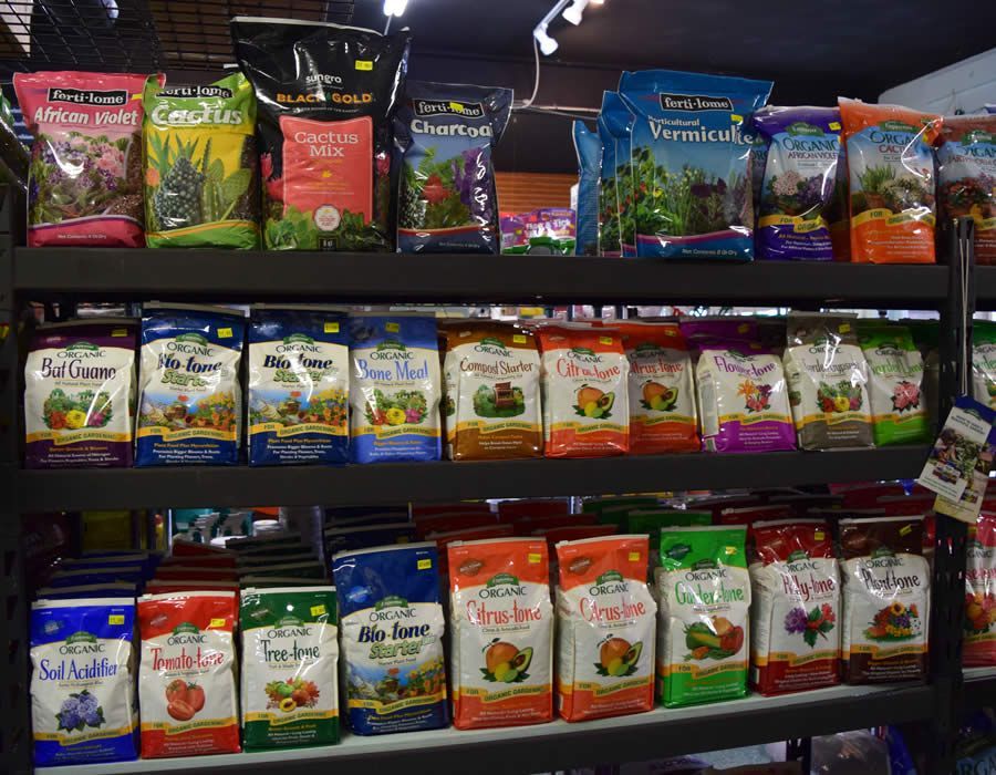Bags of gardening soil on store shelves, various brands and types.