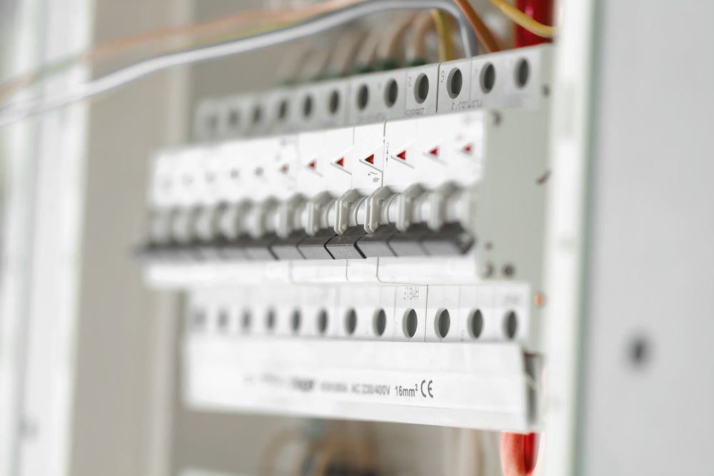 Electrical circuit breakers in a control panel, shown in close-up with white switches and red indicators.