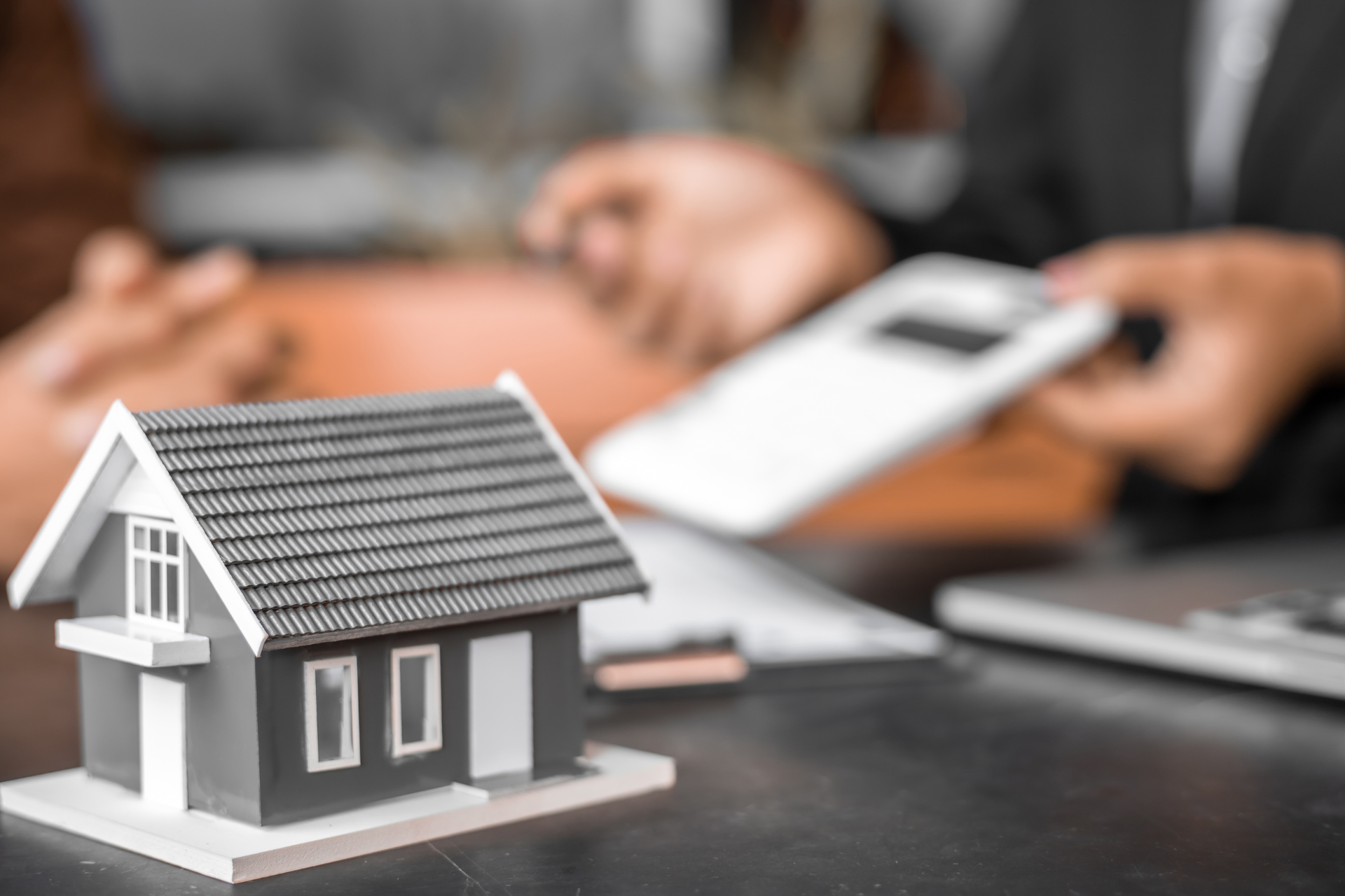 A magnifying glass is sitting on top of a graph next to two wooden houses.