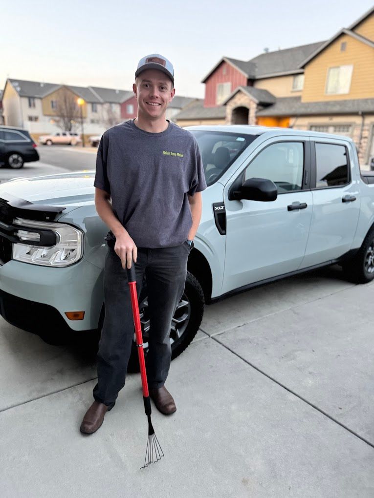 A man is standing in front of a car holding a rake