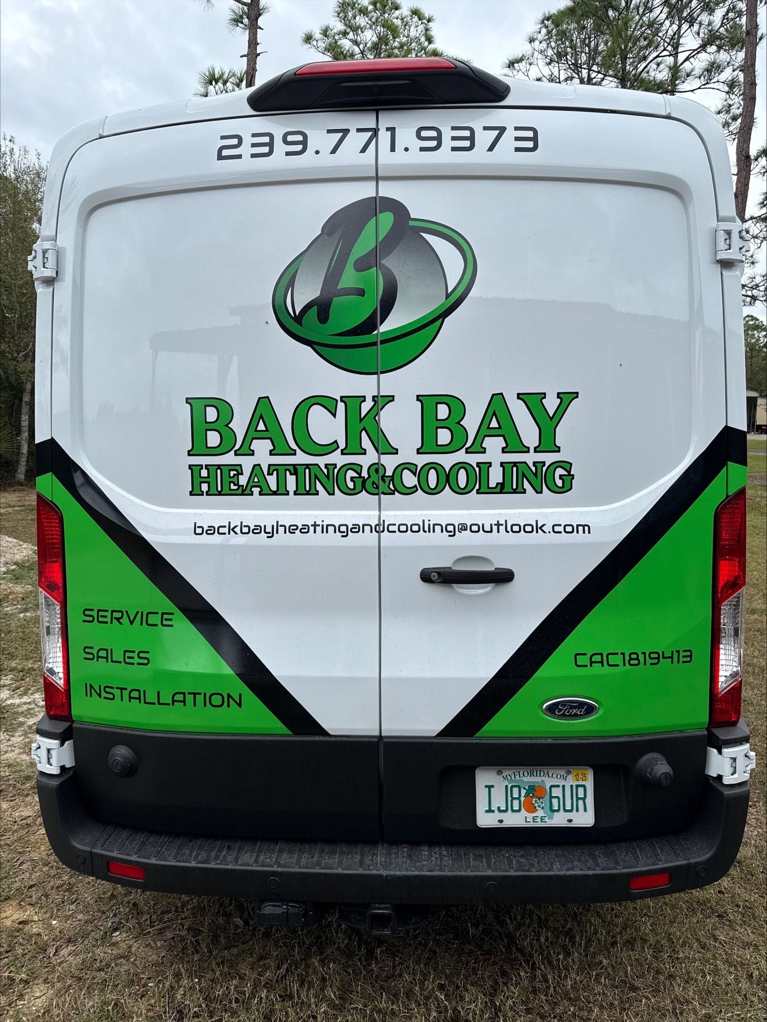 Back of a white Back Bay Heating & Cooling van with green accents and logo; phone number.