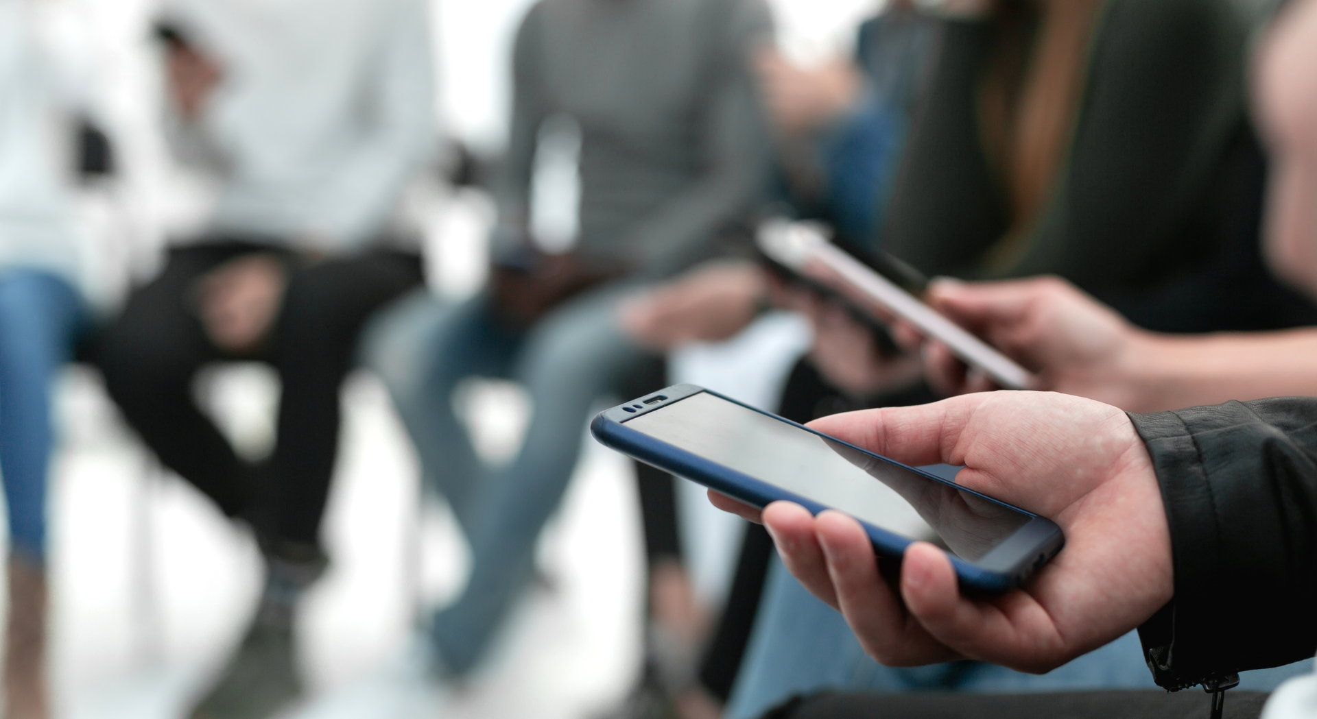 A person is holding a cell phone in their hand in front of a group of people