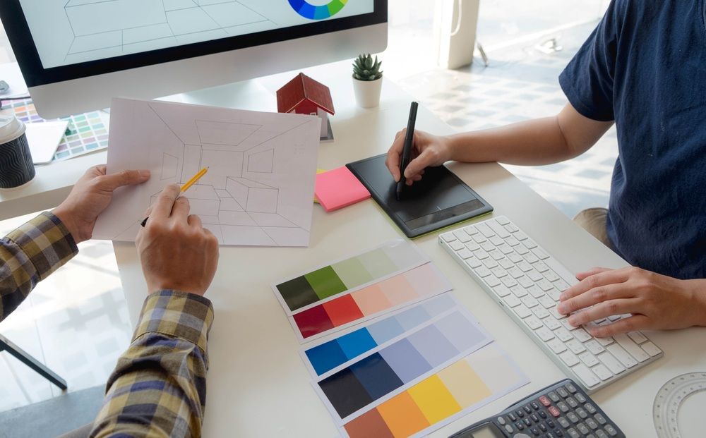 Two Men Are Sitting at a Desk Working on a Computer — Mountain City Signs In West Tamworth, NSW