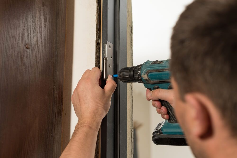 A man is installing a door with a drill — Mountain City Signs In West Tamworth, NSW