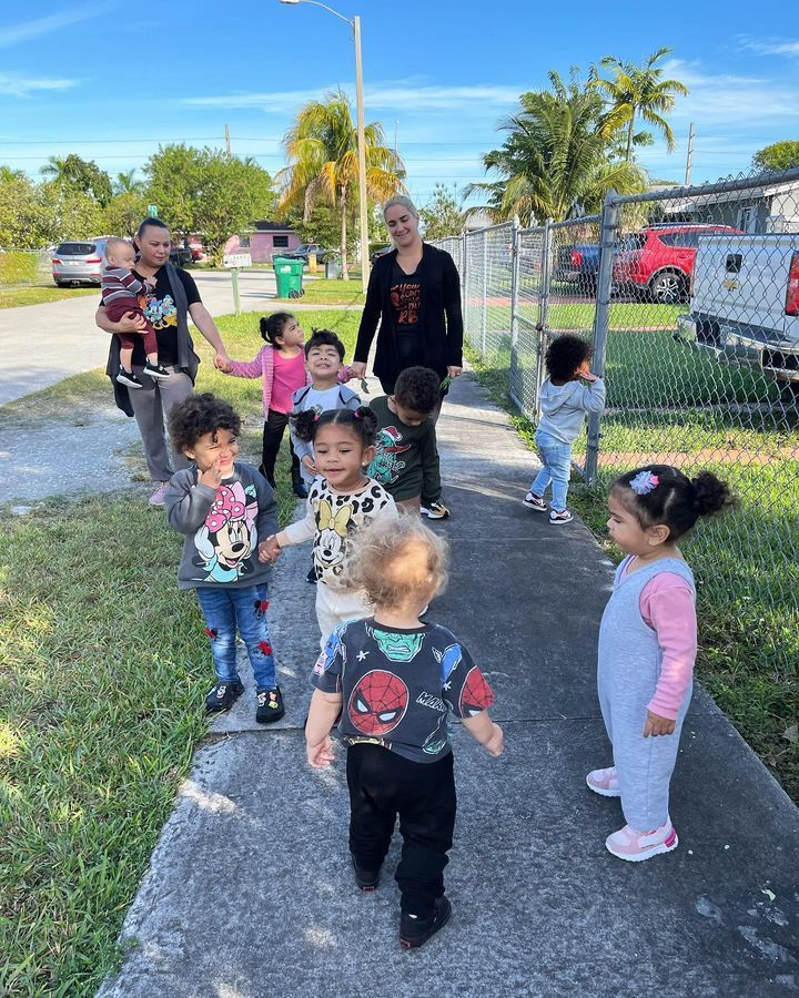 A group of children are walking down a sidewalk holding hands.