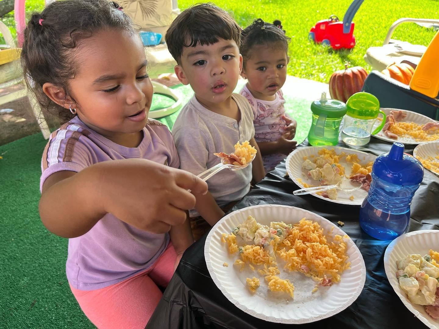 A group of children are sitting at a table eating food.