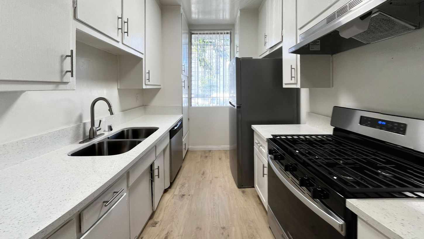Modern kitchen with white cabinets, stainless steel appliances, and a window.
