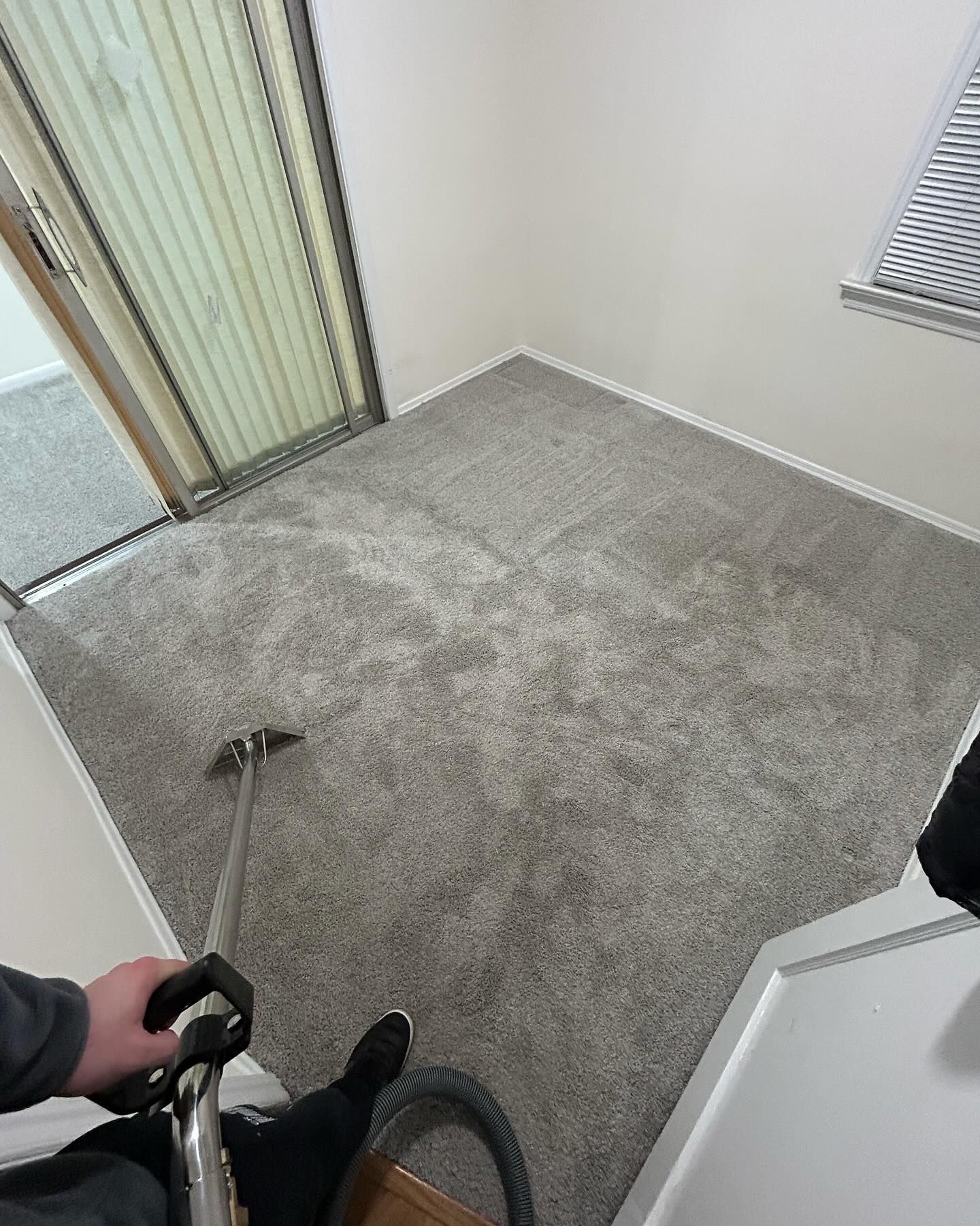 Empty carpeted room with a bicycle handlebar in the foreground and a sliding glass door.