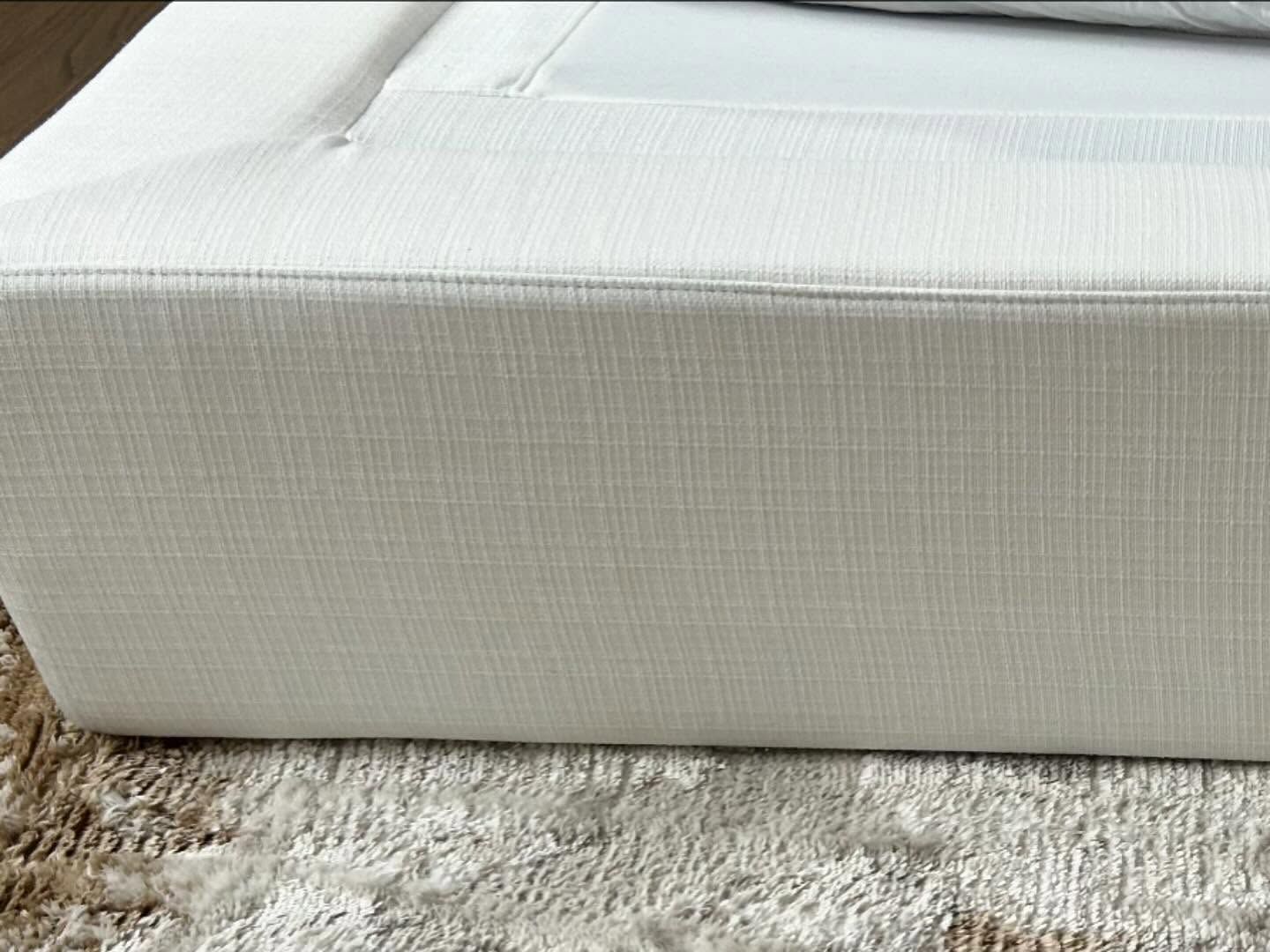 White upholstered cushion or mattress corner on a beige carpet, close-up view