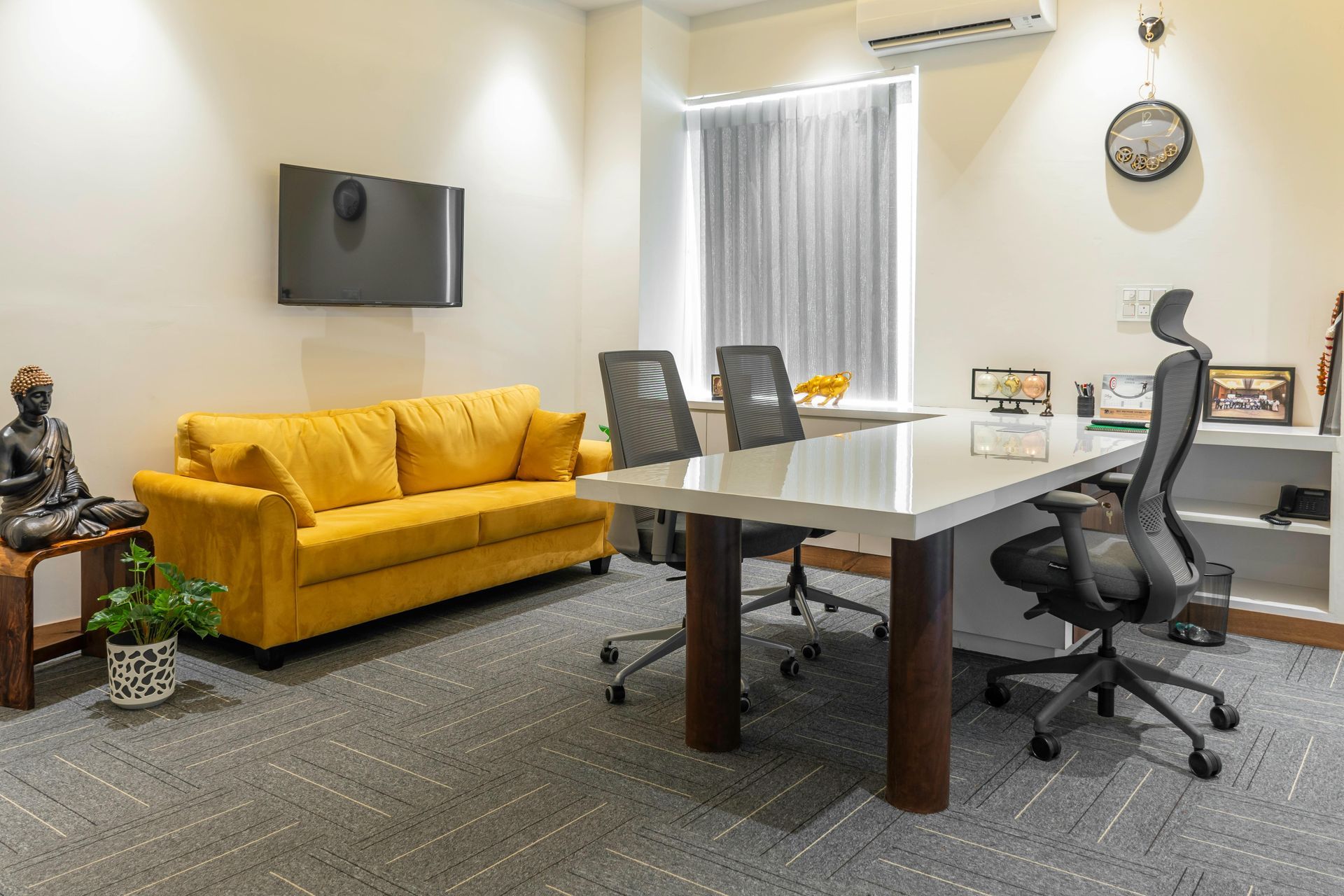 Modern office with yellow sofa, glass conference table, chairs, wall-mounted TV, and window blinds