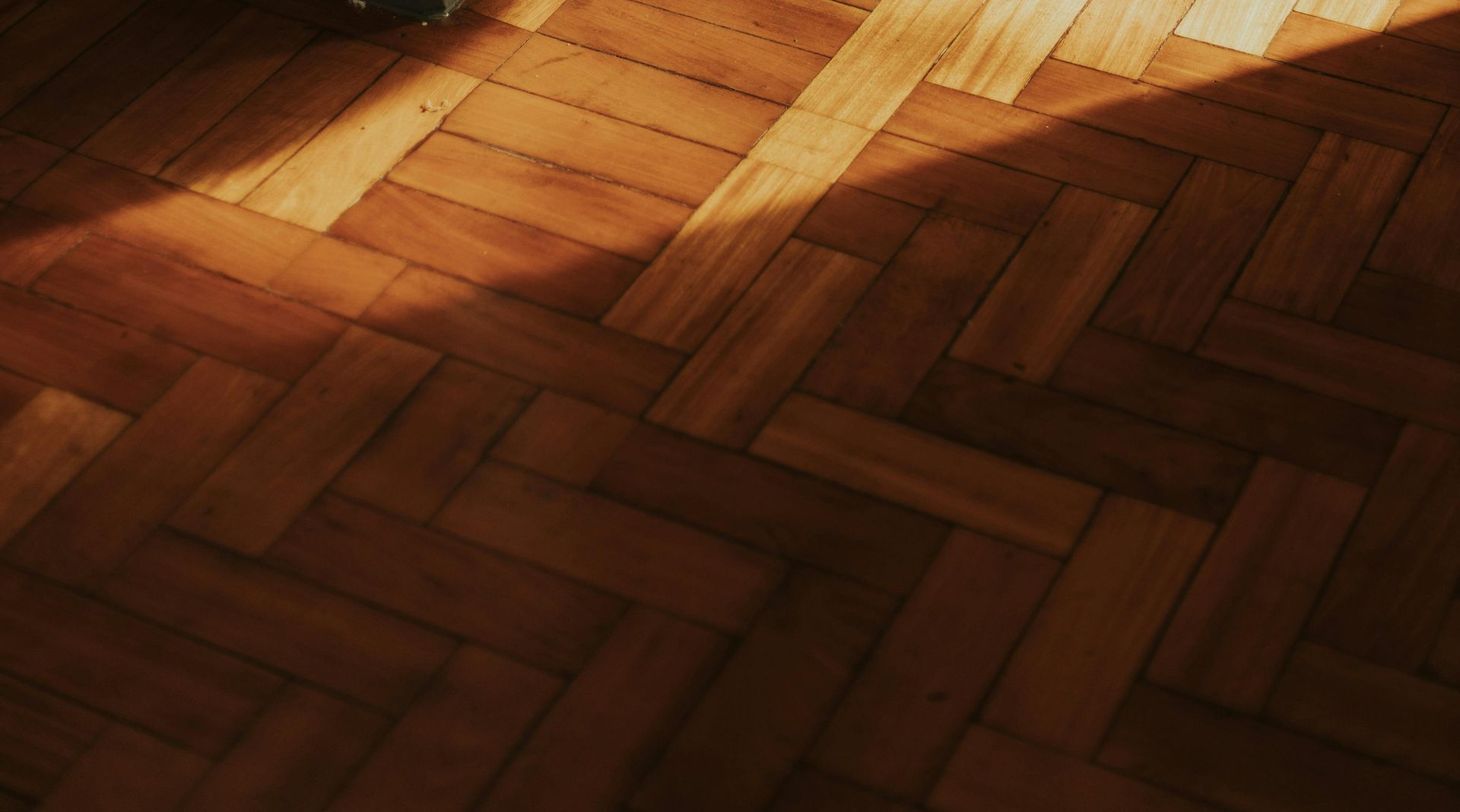 Sunlit wooden herringbone floor with diagonal shadows
