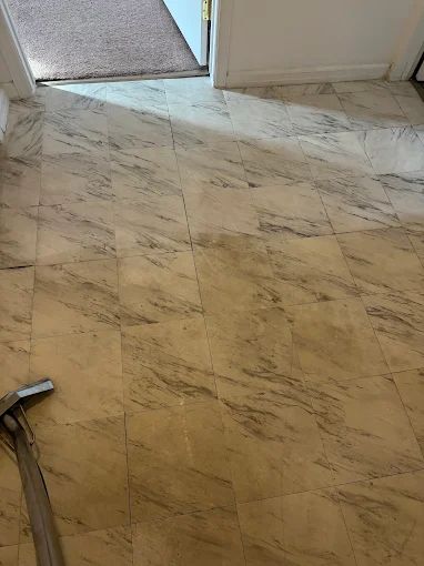 Marble-pattern tile floor by a doorway, with a broom handle in the lower left.