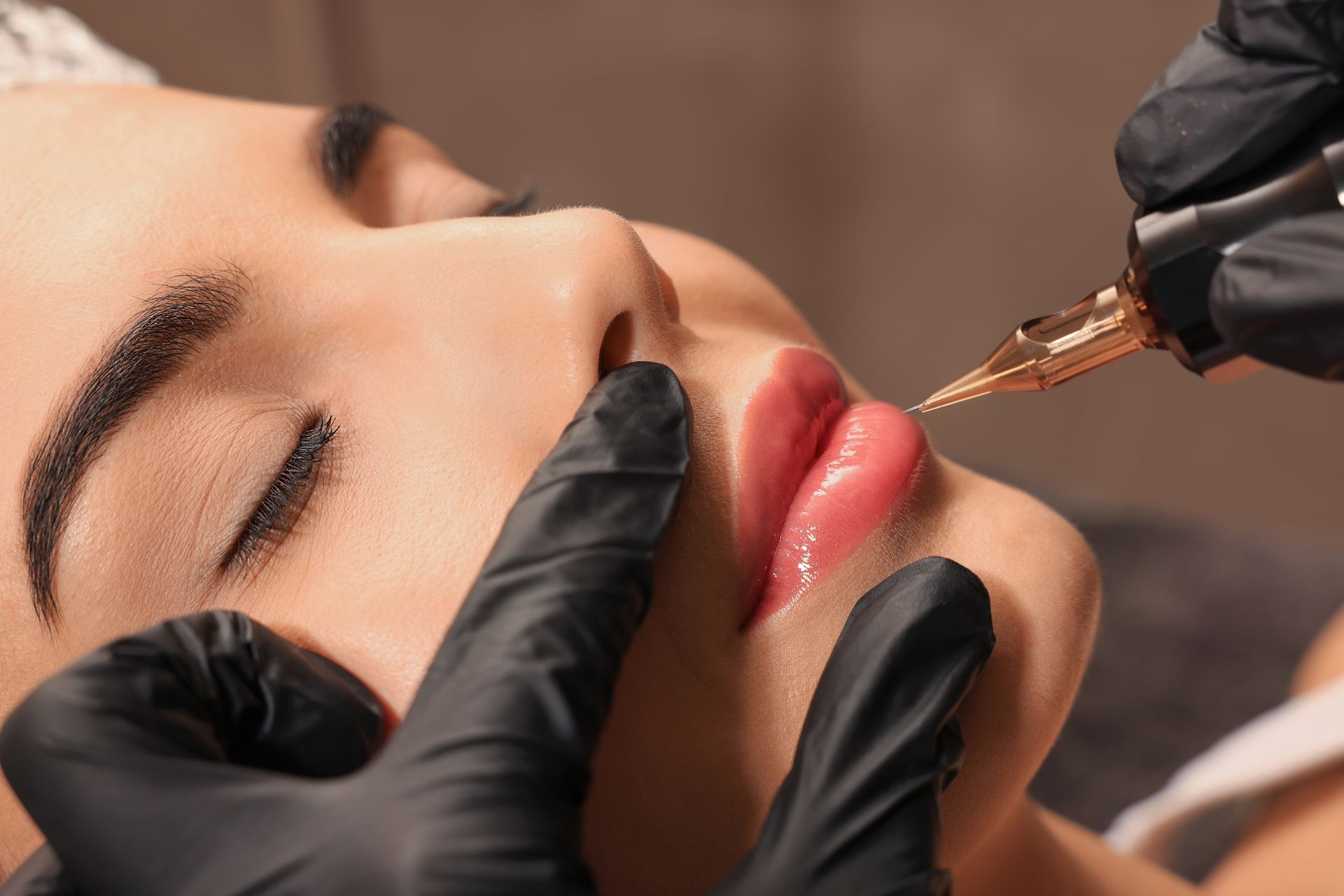 Eine Frau lässt sich ein permanentes Lippentattoo auf die Lippen stechen.