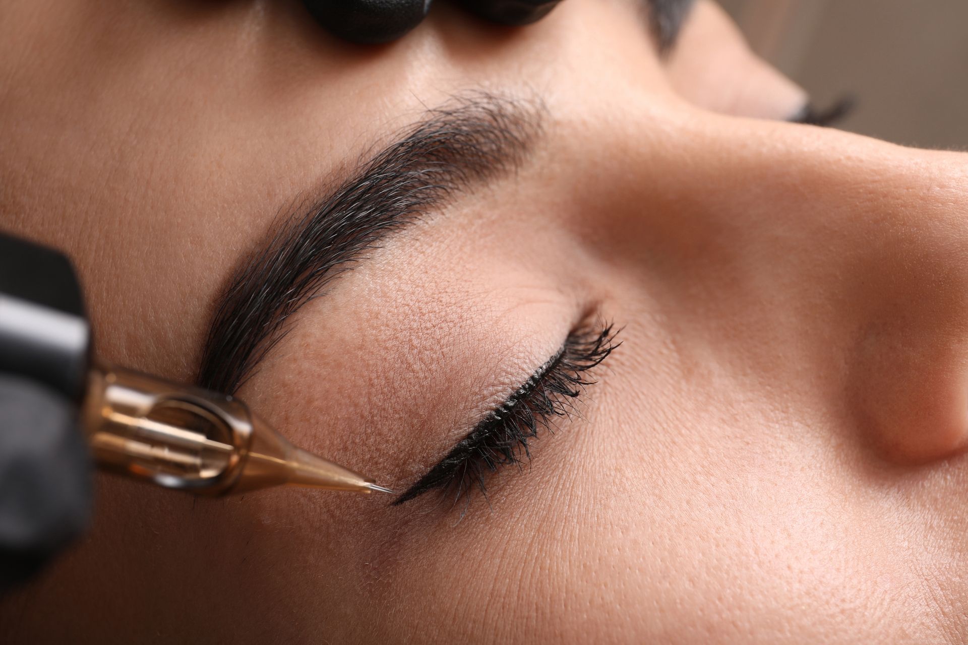Eine Frau lässt sich ein Eyeliner-Tattoo aufs Auge stechen.
