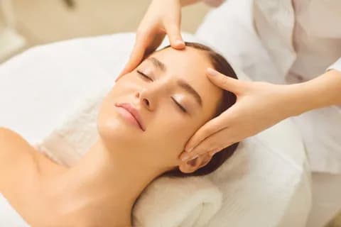 Frau-entspannt-auf-einer-Liege-und-bekommt-Gesichtsmassage
