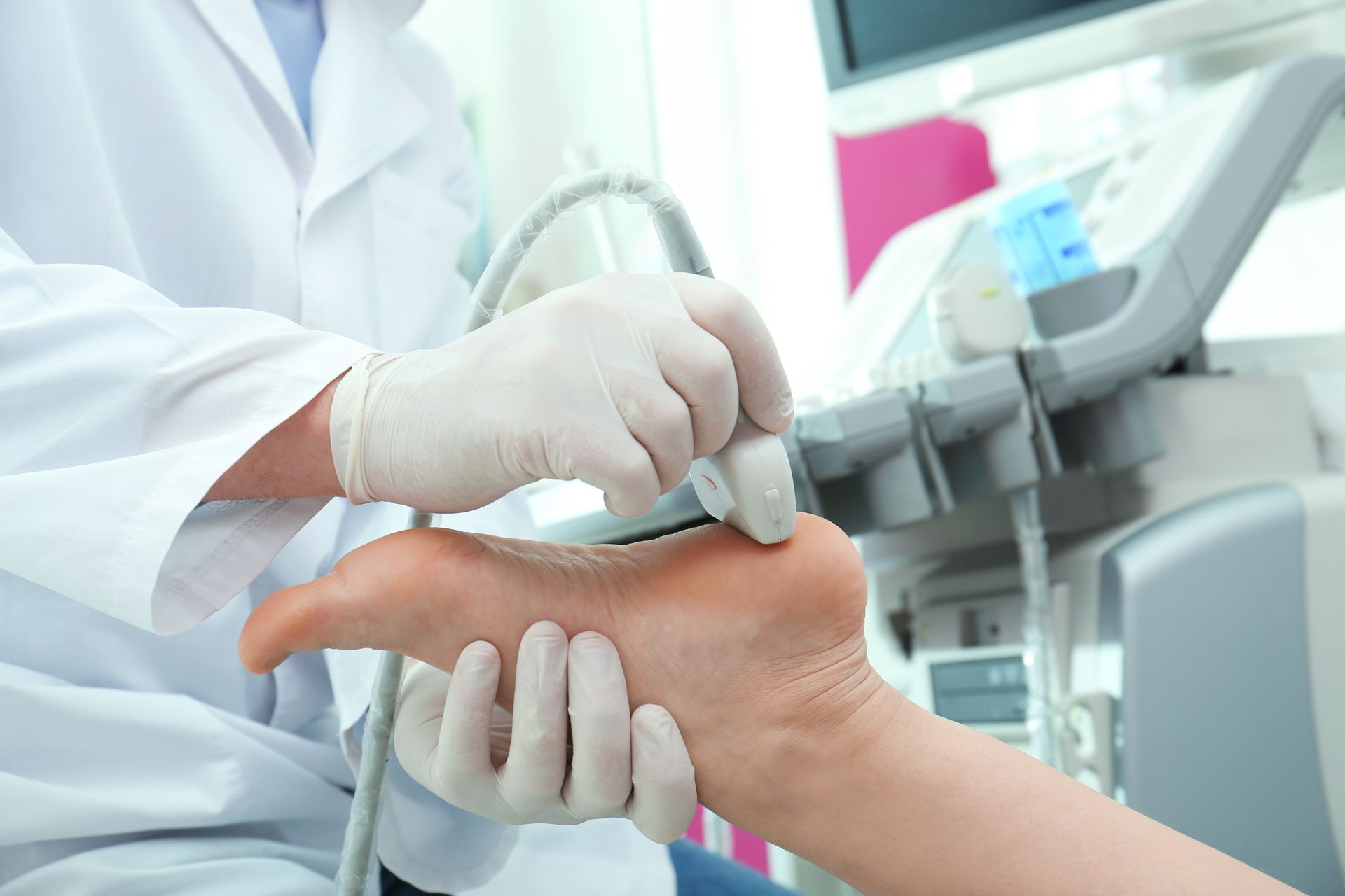 A doctor wearing gloves uses an ultrasound machine on a patient's foot.
