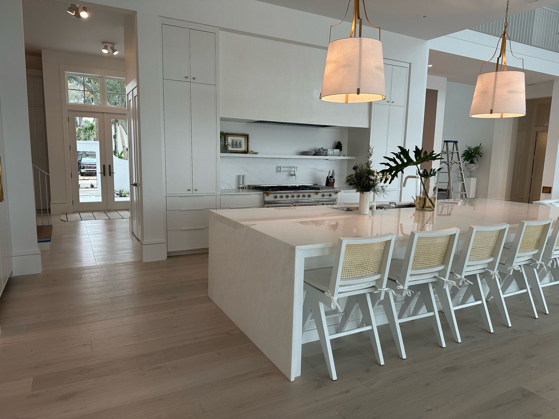 White kitchen with island seating and pendant lights.