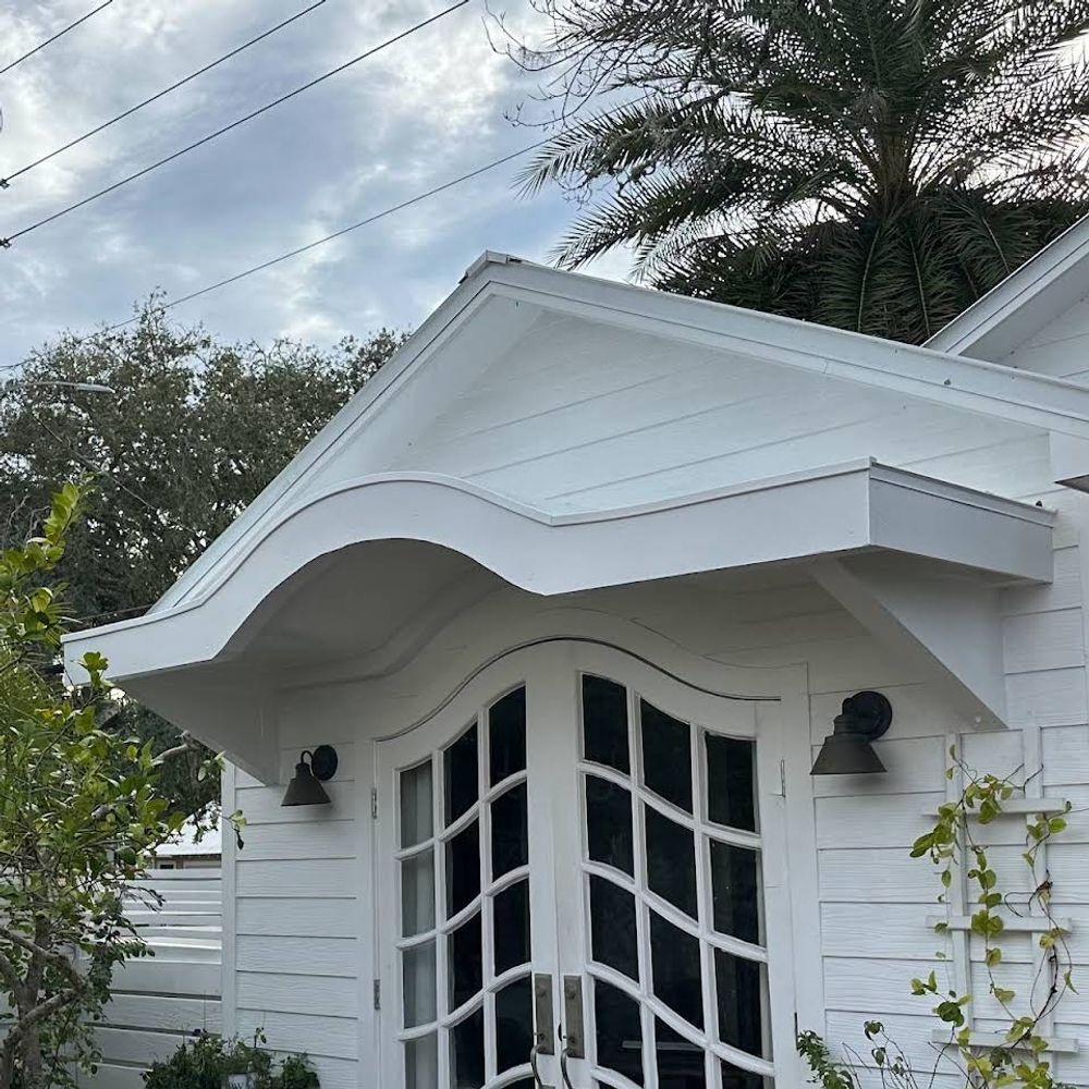 White building facade with curved awning and double doors.