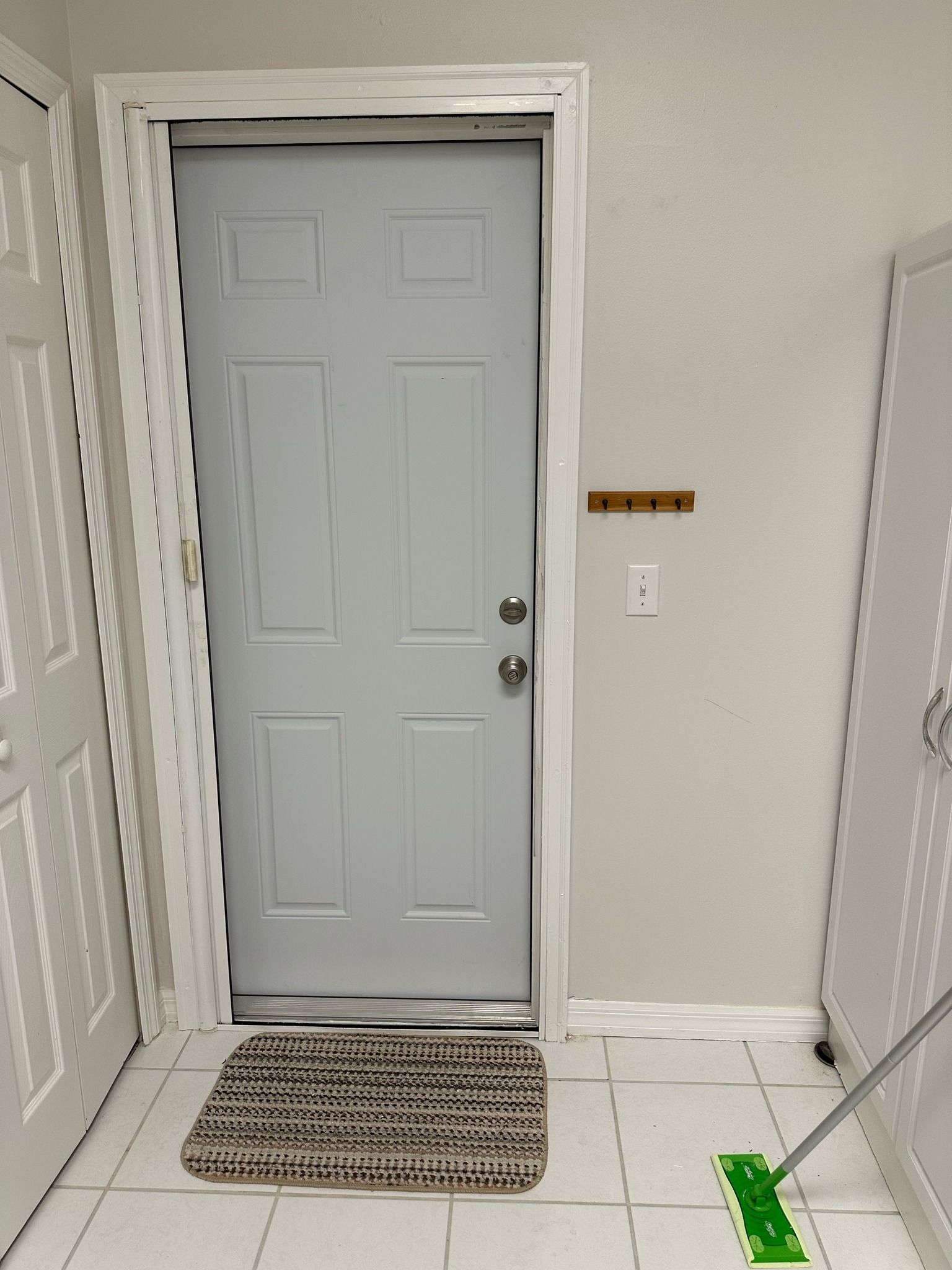 A light blue interior door with a rug in front, located between two white doors and a wall.
