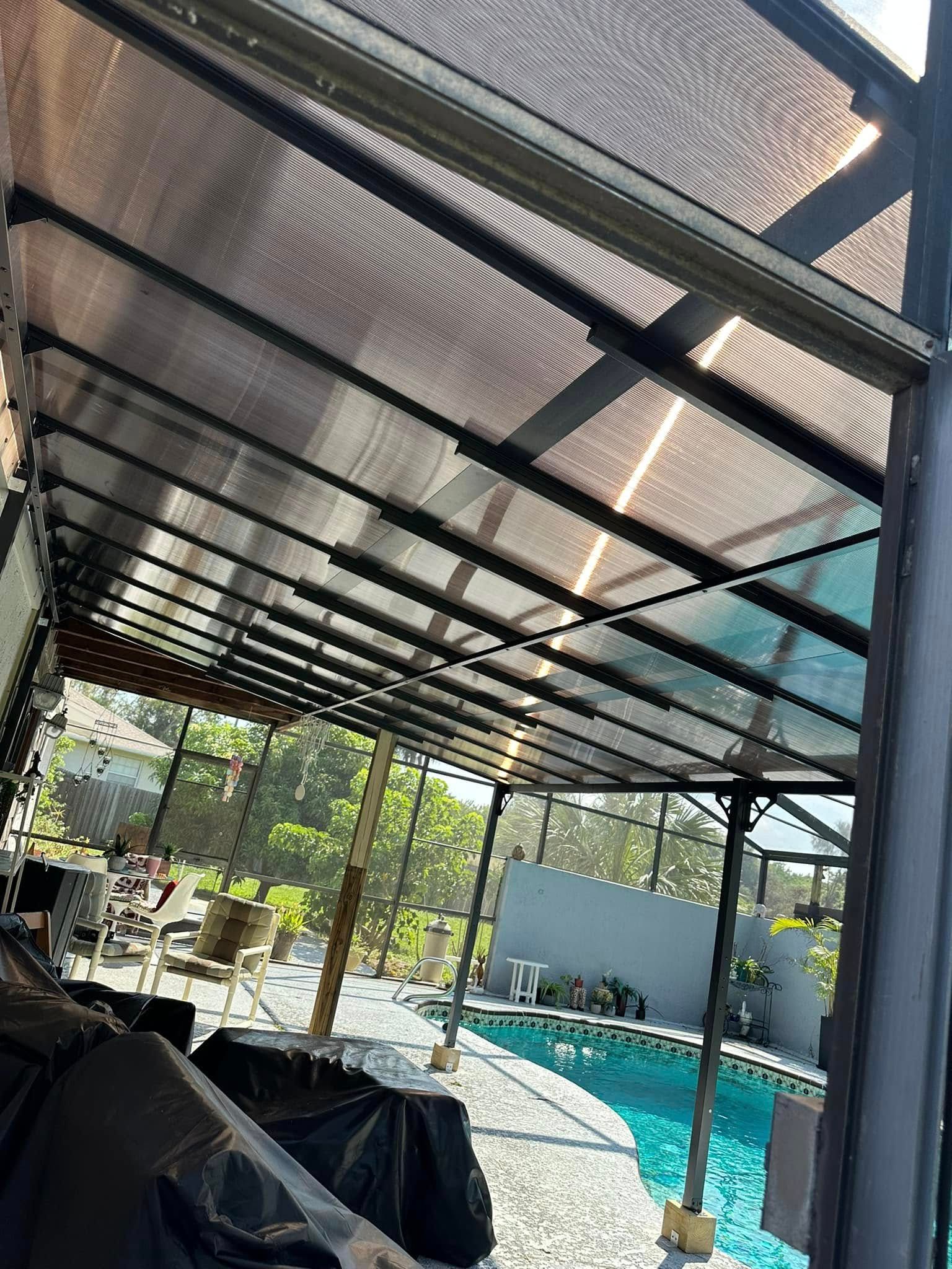 Black framed patio roof over a pool. Translucent panels allow sunlight.