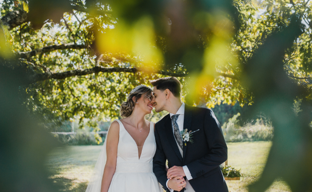 Bride and groom embracing under trees
