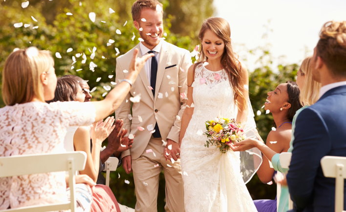 Bride and groom walking back up the aisle as guests congratulate them
