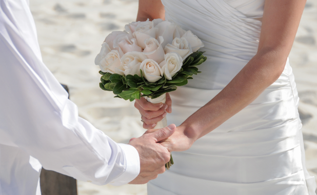Couple holding hands with a white rose bouquet
