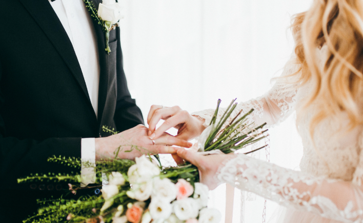 Groom placing a ring on the bride's finger