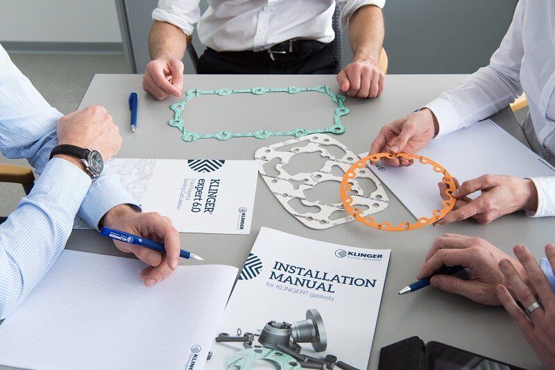 discussion around table with KLINGER brochures and gaskets