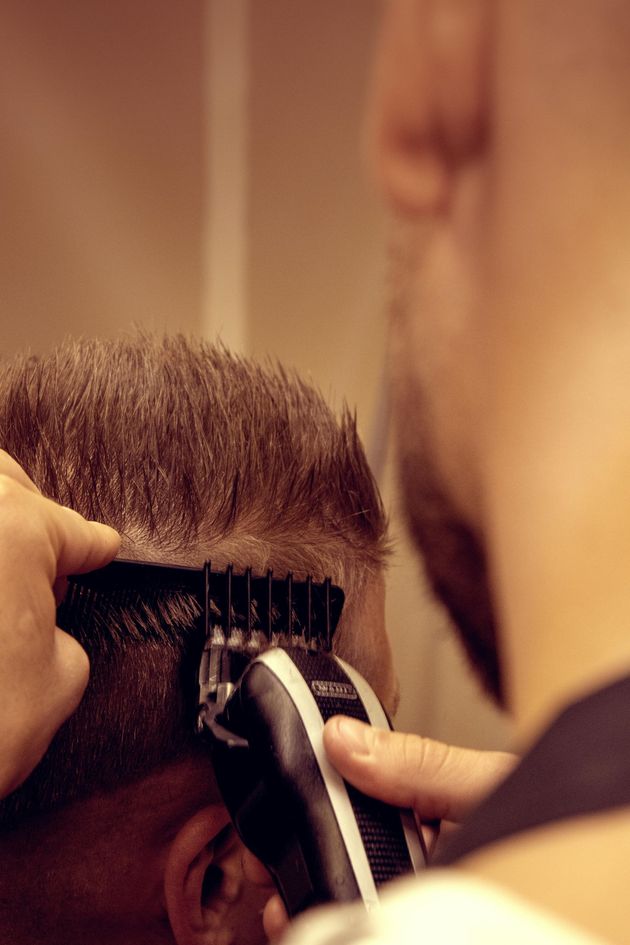 Primer plano de una maquinilla cortando el pelo de una persona en una barbería.