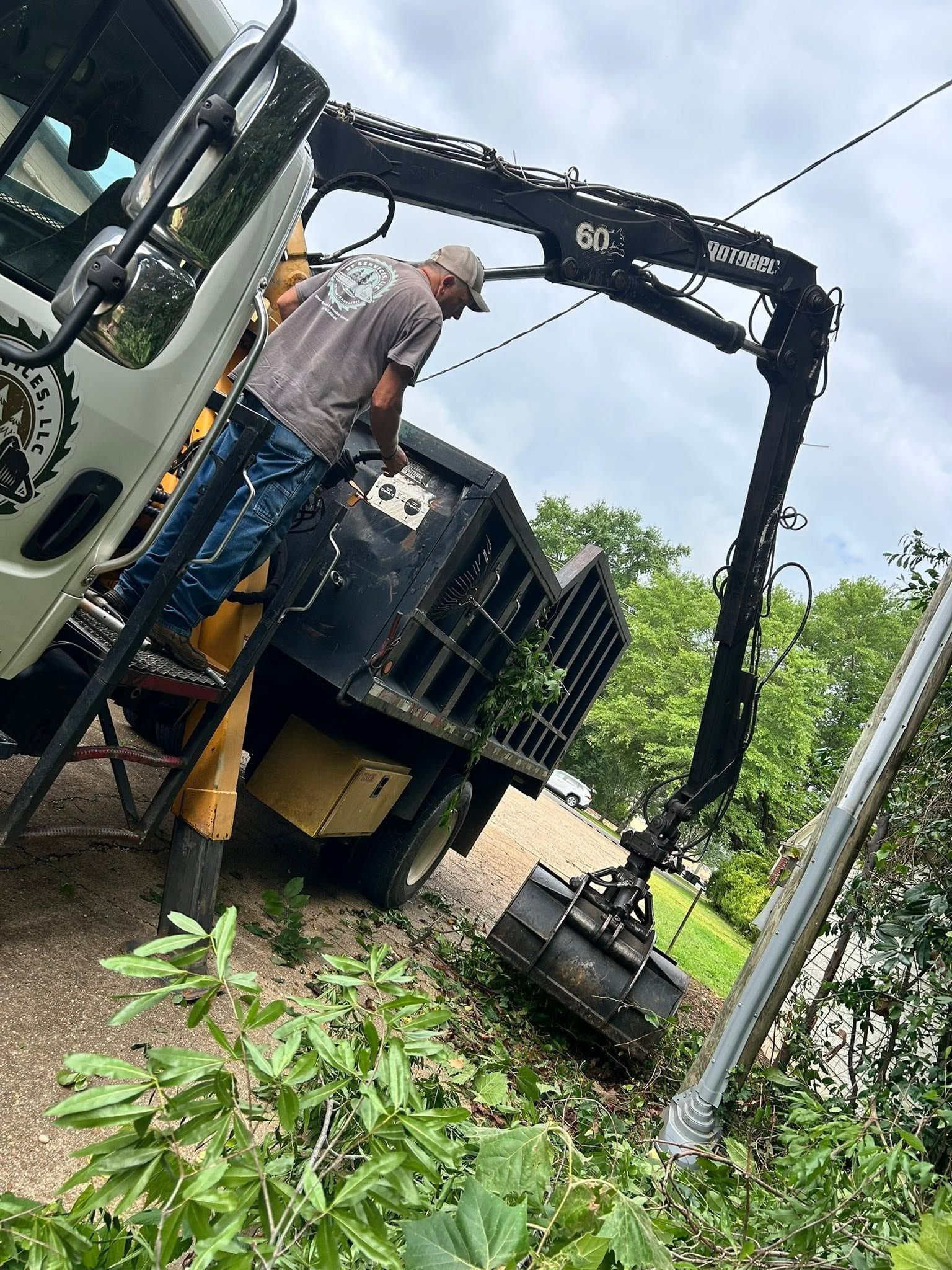 Worker beside black truck-mounted crane in a grassy field after rain