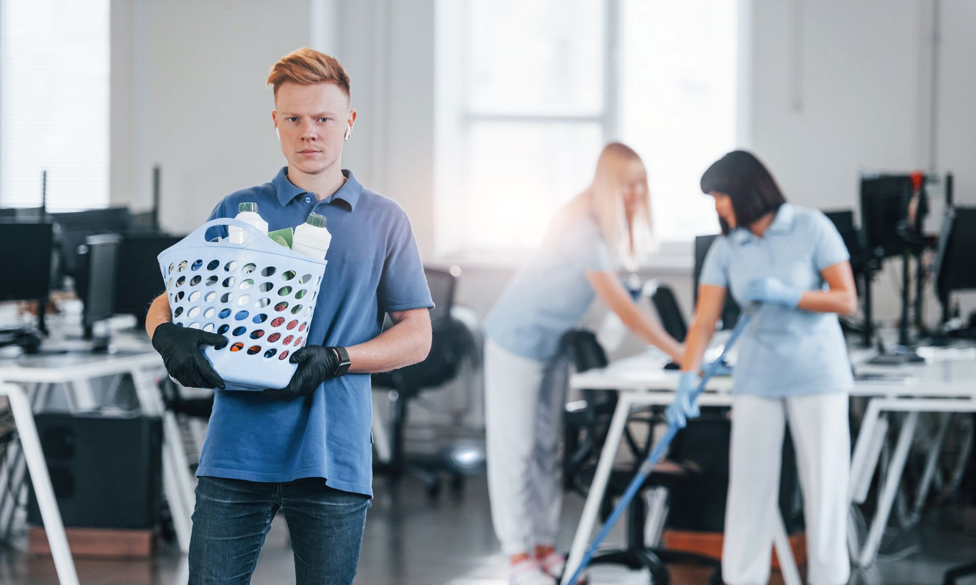 A man is holding a laundry basket in an office.