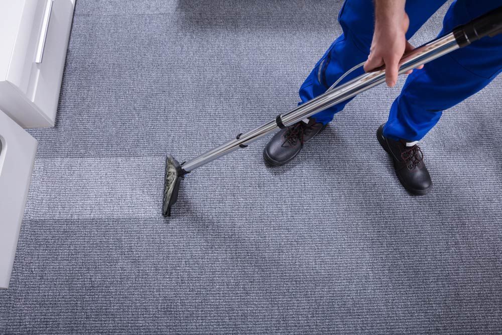 A Man Cleaning Carpet With Vacuum Cleaner — Big Red Carpet & Property Maintenance In Bowen, QLD