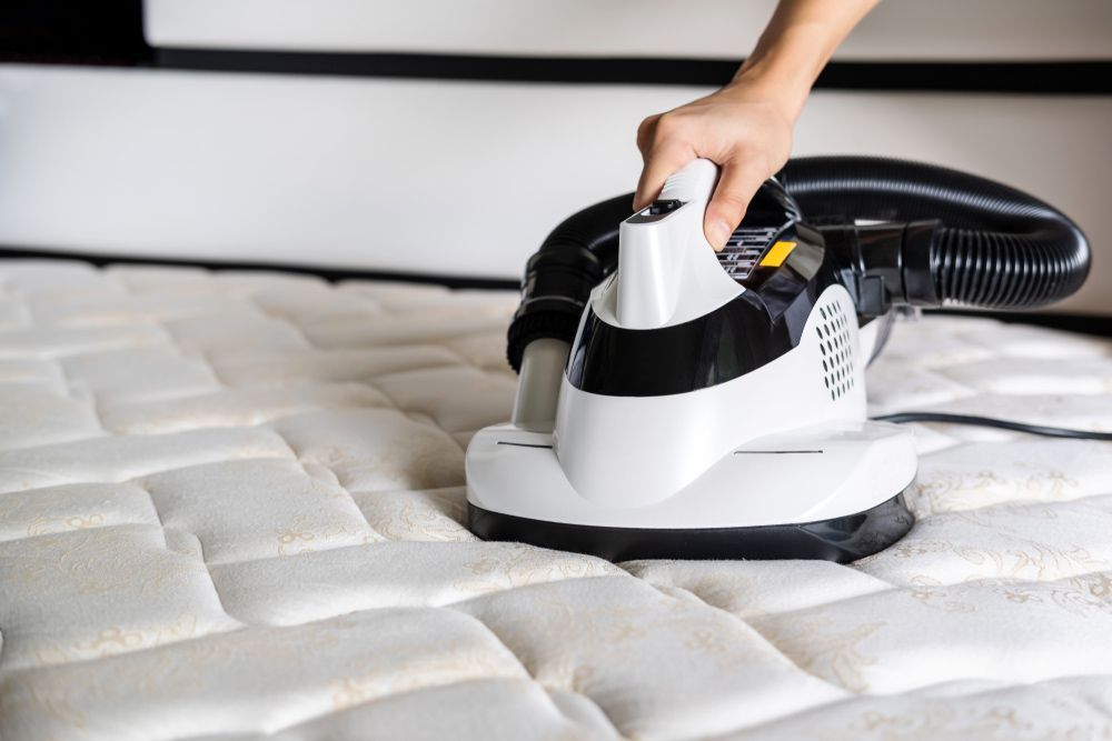 A Person Is Cleaning A Mattress With A Vacuum Cleaner — Big Red Carpet & Property Maintenance In Collinsville, QLD A Person Is Cleaning A Mattress With A Vacuum Cleaner — Big Red Carpet & Property Maintenance In Collinsville, QLD