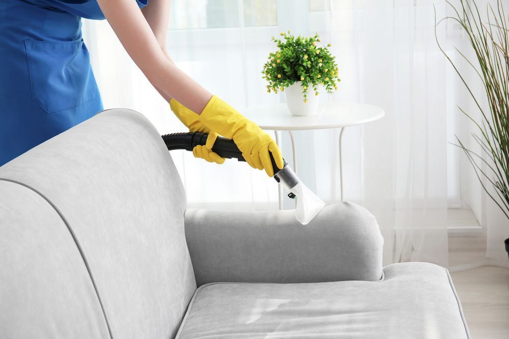 Woman Cleaning Couch With Vacuum Cleaner — Big Red Carpet & Property Maintenance In Bowen, QLD