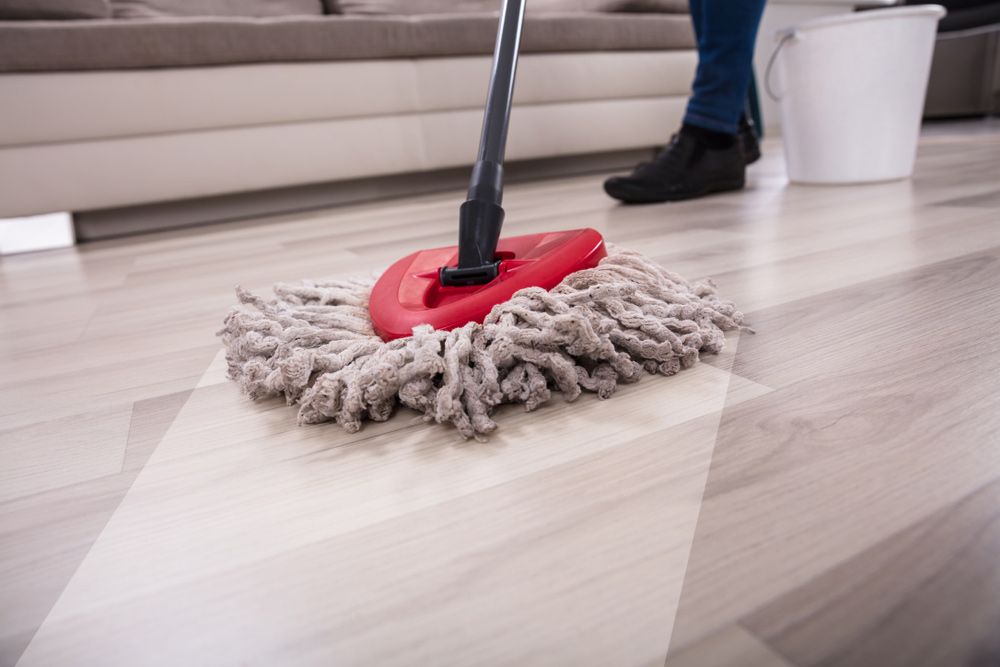 A Person Cleaning Hardwood Floor With Mop — Big Red Carpet & Property Maintenance In Bowen, QLD