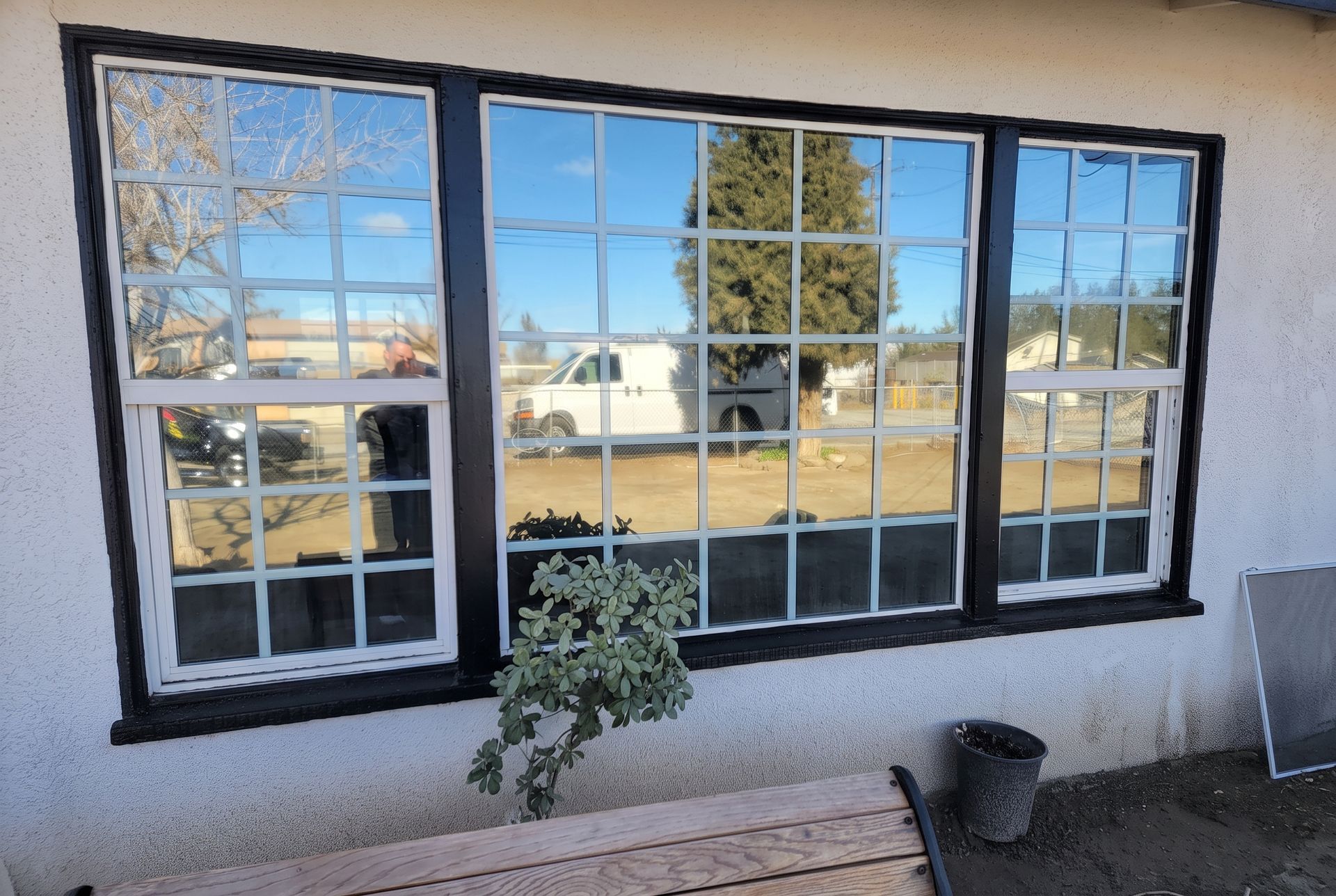 Reflective storefront windows showing parked cars and a residential street outside