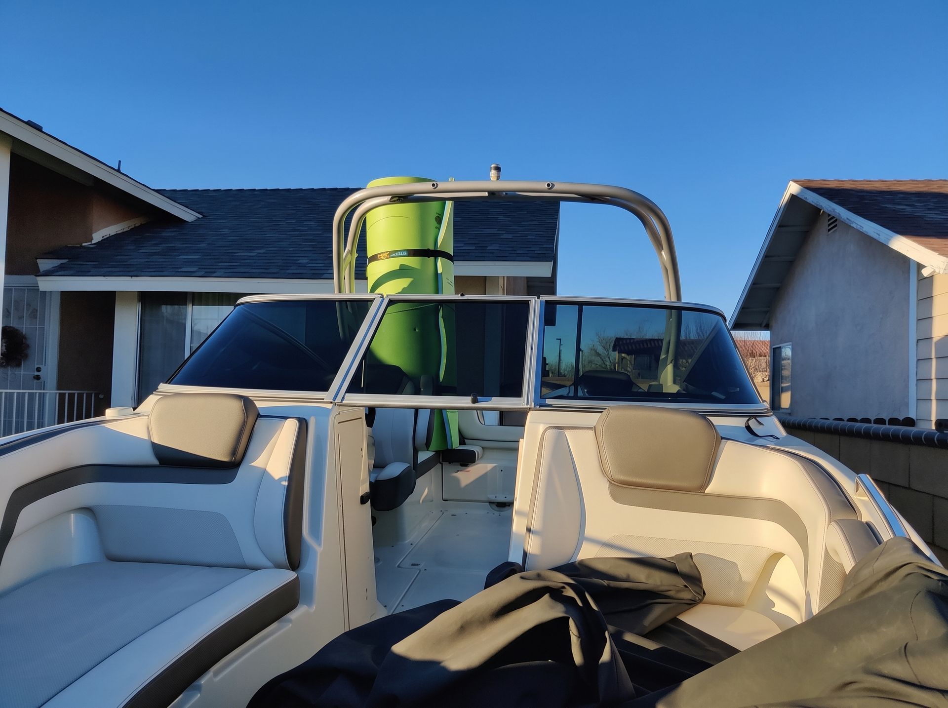 Seated view from a boat toward a green water slide between houses on a dock at sunset.