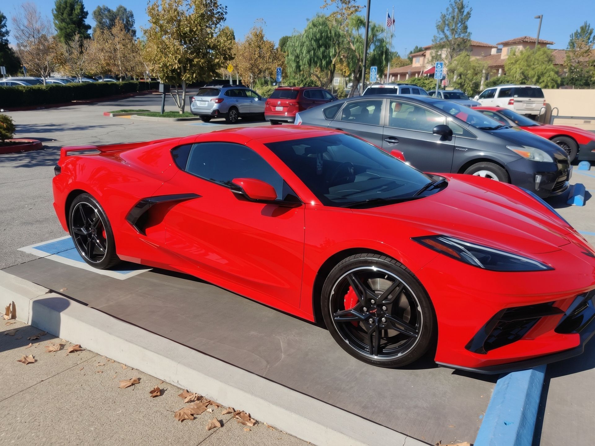Red sports car parked outdoors in a lot on a sunny day