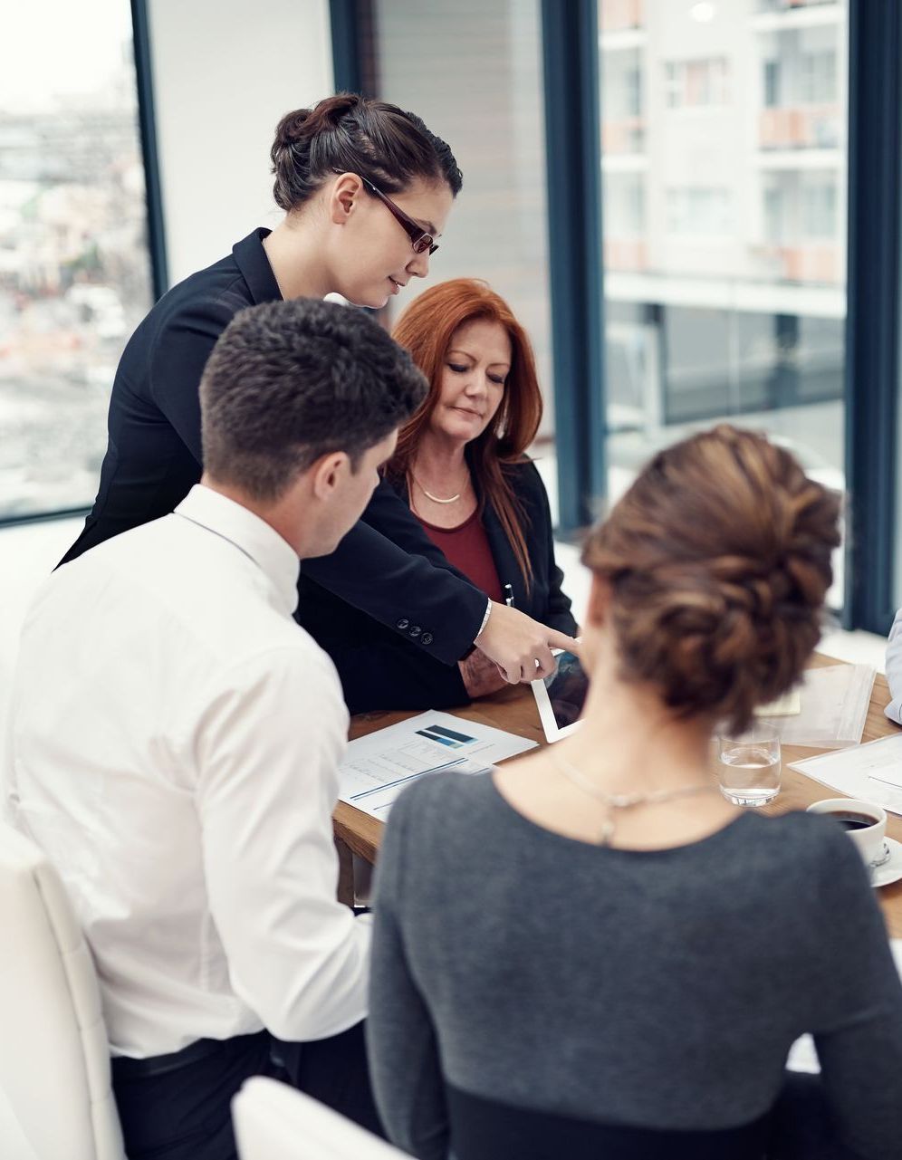 People in an office in around a table discussing.