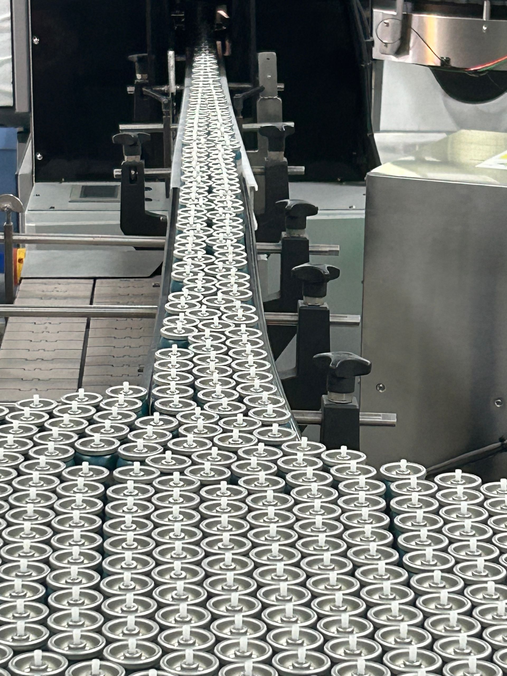 A conveyor belt is filled with lots of aerosol cans.