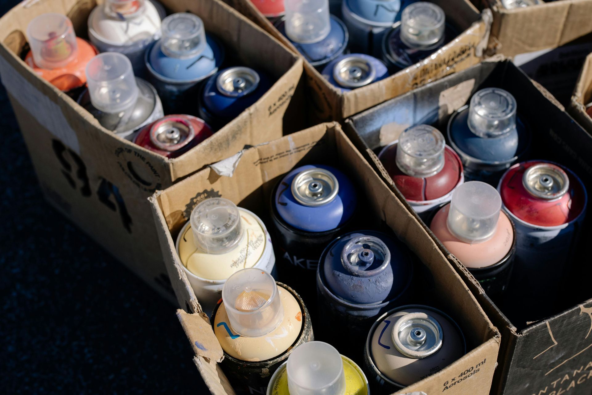 Multiple cardboard boxes filled with aerosol cans standing upright.