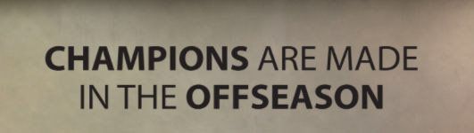 Text on a wall reads, “CHAMPIONS ARE MADE IN THE OFFSEASON.”