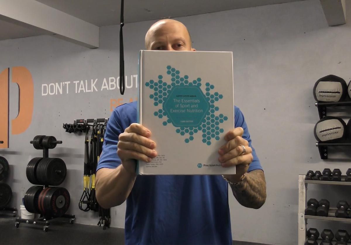 Person in a gym holding a booklet with a blue circular design in front of their face