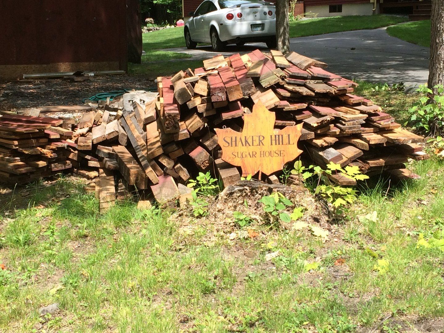 Wooden SHARE THE ROAD sign in front of a stacked-brick sculpture on a grassy roadside with a car behind it